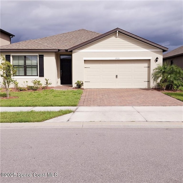 ranch-style house with a garage, roof with shingles, decorative driveway, a front yard, and stucco siding