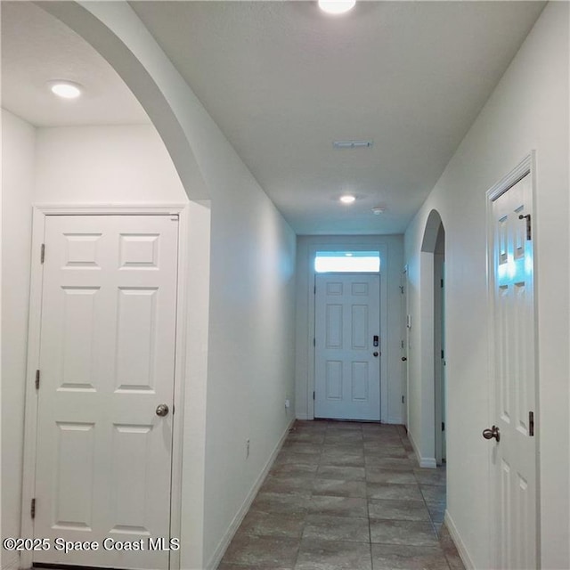 corridor with arched walkways and baseboards