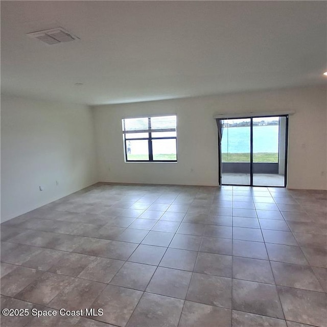 spare room featuring a wealth of natural light, visible vents, and tile patterned floors