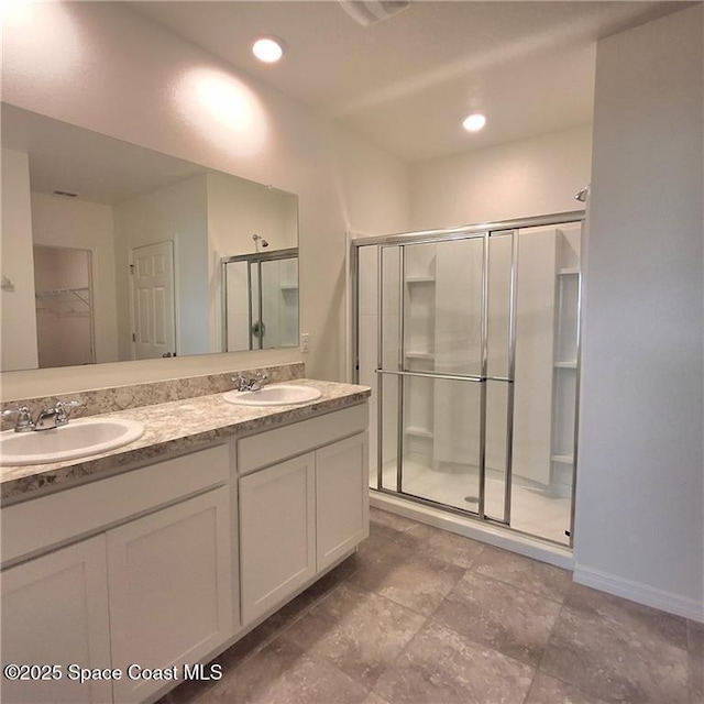 full bathroom with double vanity, a shower stall, a spacious closet, and a sink