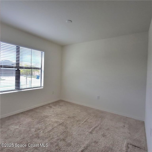 spare room featuring carpet and baseboards