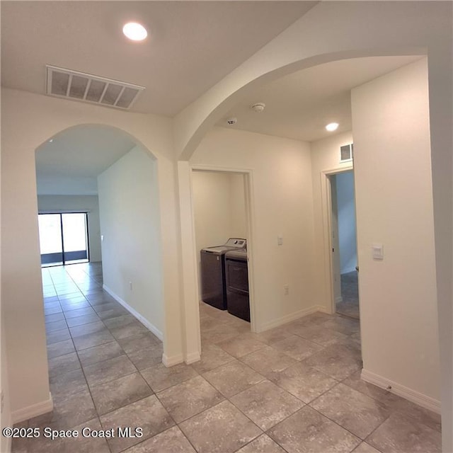 hall with washer / dryer, arched walkways, visible vents, and baseboards