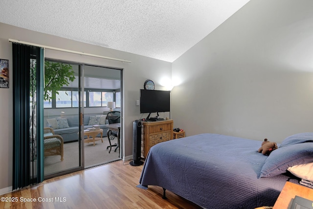 bedroom featuring lofted ceiling, baseboards, a textured ceiling, and light wood finished floors