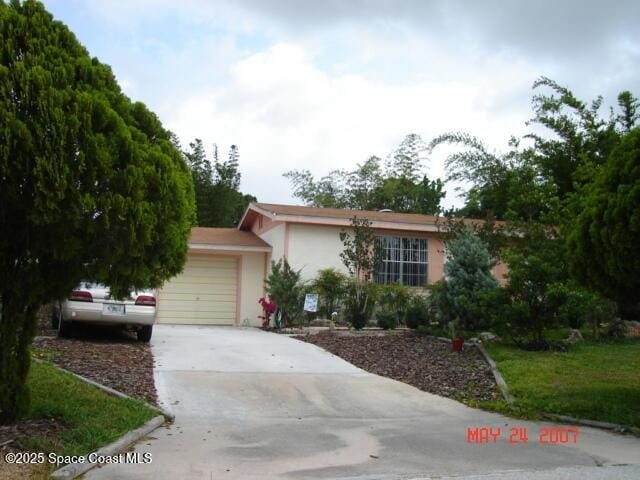 ranch-style home with a garage, concrete driveway, and stucco siding