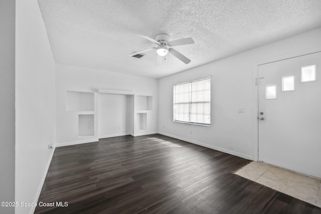 entrance foyer with visible vents, baseboards, dark wood-style floors, ceiling fan, and a textured ceiling