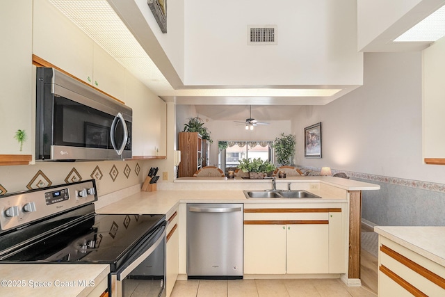 kitchen with ceiling fan, stainless steel appliances, a peninsula, visible vents, and light countertops