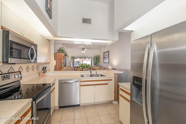 kitchen with stainless steel appliances, a peninsula, a sink, visible vents, and light countertops