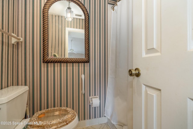 bathroom with baseboards, tile patterned floors, toilet, and wallpapered walls