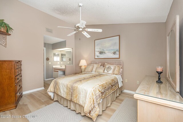 bedroom featuring a textured ceiling, visible vents, baseboards, vaulted ceiling, and light wood-style floors