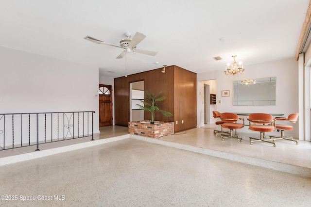 interior space with light speckled floor, visible vents, and ceiling fan with notable chandelier