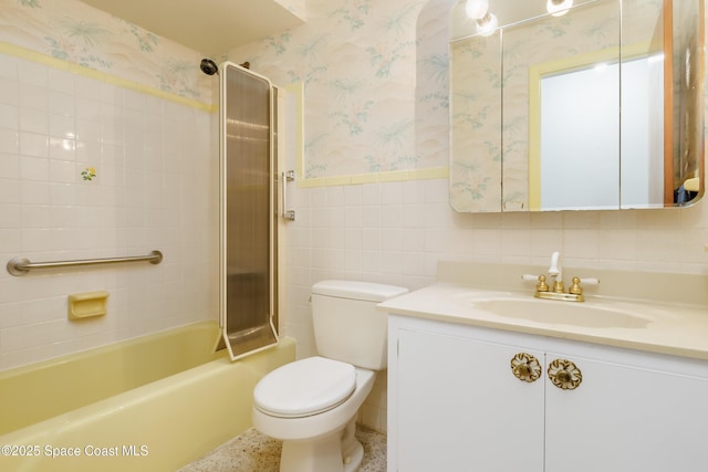 full bathroom with a wainscoted wall, tile walls, bathtub / shower combination, toilet, and wallpapered walls