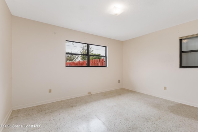 unfurnished room featuring baseboards and speckled floor