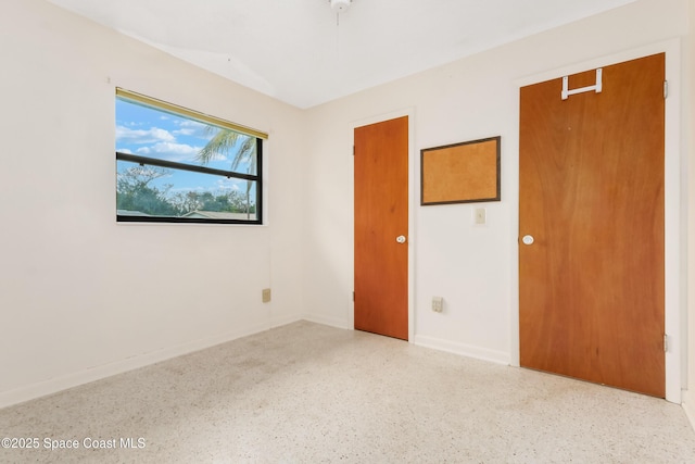 unfurnished bedroom with speckled floor and baseboards