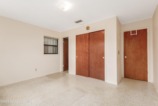 unfurnished bedroom with visible vents, light speckled floor, and a closet