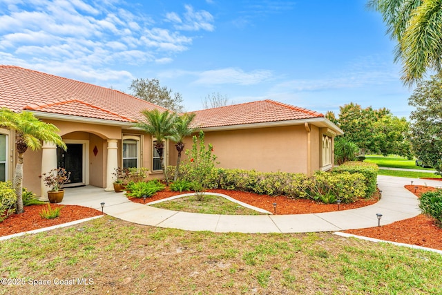 mediterranean / spanish-style house with a front lawn, a tile roof, and stucco siding