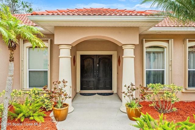 view of exterior entry featuring a tile roof and stucco siding