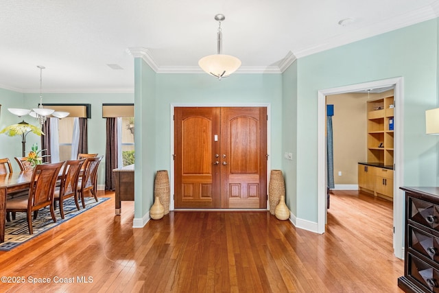 foyer entrance with baseboards, ornamental molding, and light wood-style floors