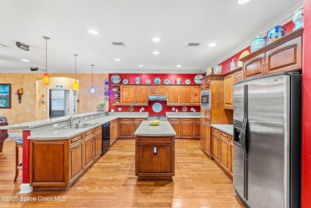 kitchen featuring stainless steel appliances, a peninsula, a sink, a center island, and decorative light fixtures