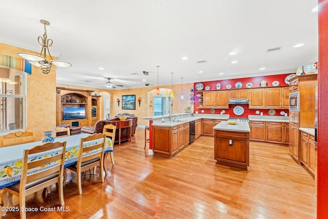 kitchen featuring a peninsula, a kitchen island, open floor plan, hanging light fixtures, and light countertops