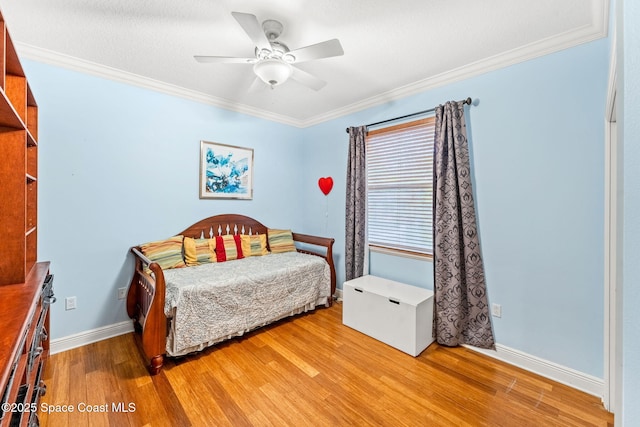 bedroom featuring baseboards, ornamental molding, a ceiling fan, and light wood-style floors