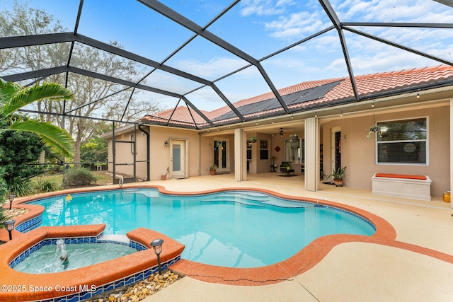 view of pool featuring glass enclosure, a patio area, a pool with connected hot tub, and a ceiling fan