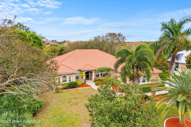 mediterranean / spanish house with a tiled roof, a front lawn, and stucco siding