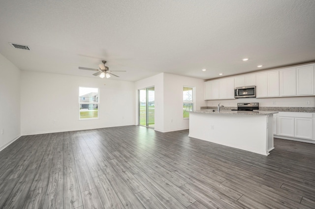 kitchen with visible vents, white cabinets, appliances with stainless steel finishes, open floor plan, and a sink