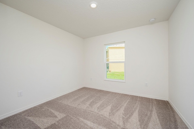 carpeted spare room featuring baseboards and a textured ceiling