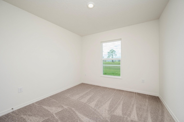 unfurnished room with a textured ceiling, carpet, and baseboards