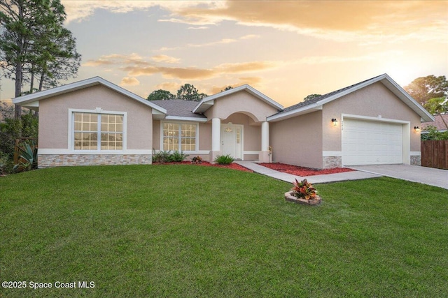 single story home featuring stone siding, a lawn, driveway, and stucco siding