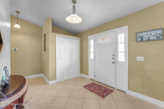 foyer featuring light tile patterned floors, baseboards, and vaulted ceiling