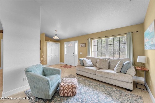 living room with light tile patterned floors, a textured ceiling, arched walkways, and baseboards