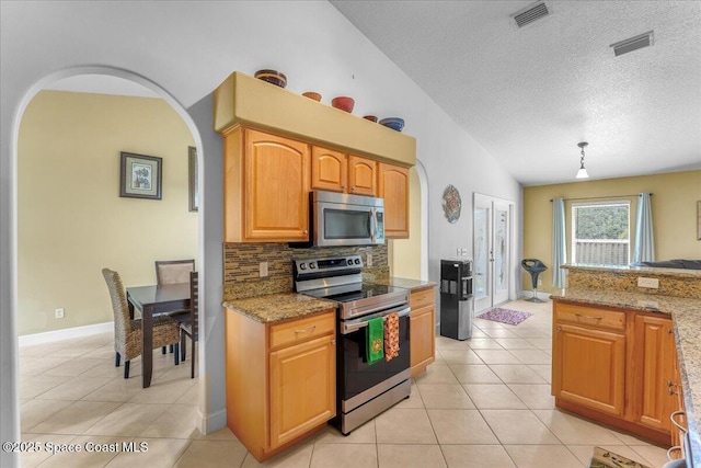 kitchen with arched walkways, light tile patterned floors, visible vents, appliances with stainless steel finishes, and light stone countertops