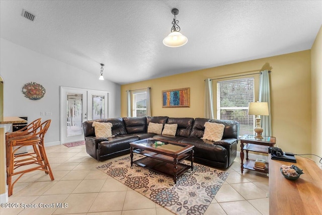 living area featuring lofted ceiling, light tile patterned floors, visible vents, and a wealth of natural light