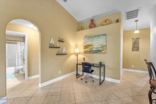 office space featuring arched walkways, light tile patterned floors, vaulted ceiling, and visible vents