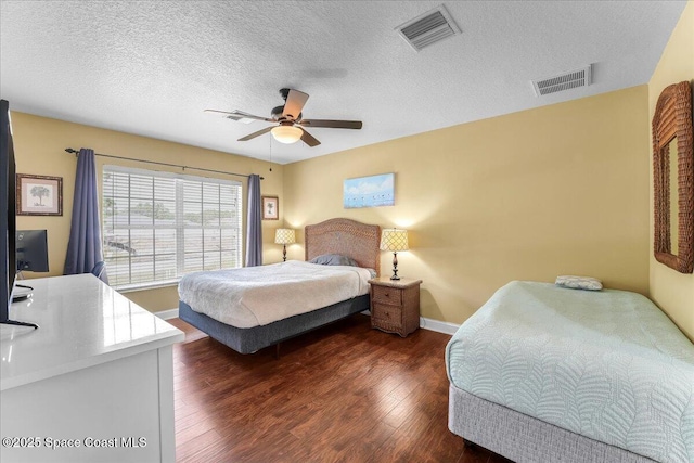 bedroom featuring dark wood-style floors, visible vents, a textured ceiling, and baseboards