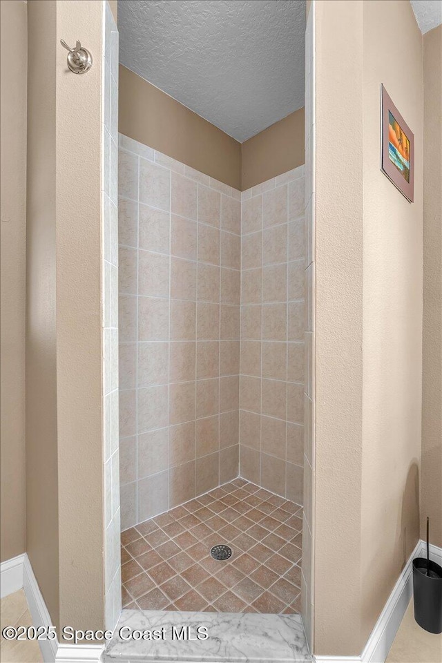 full bath with tiled shower and a textured ceiling