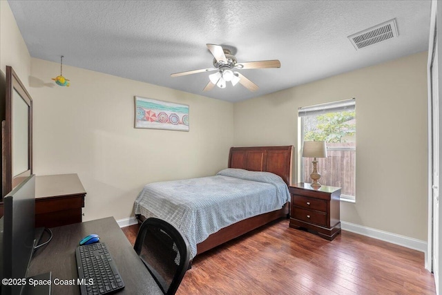 bedroom featuring dark wood-style floors, baseboards, visible vents, and a textured ceiling