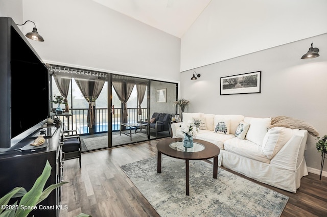 living area featuring wood finished floors, baseboards, and high vaulted ceiling