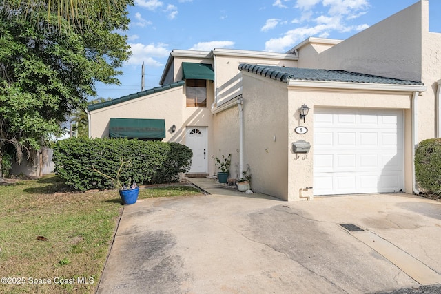 view of front of house featuring concrete driveway, an attached garage, a tiled roof, and stucco siding