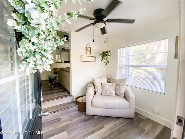 sitting room with a ceiling fan, baseboards, and light wood finished floors