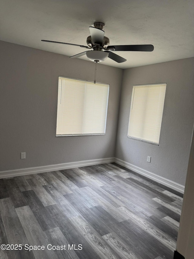 spare room featuring dark wood-style floors and baseboards