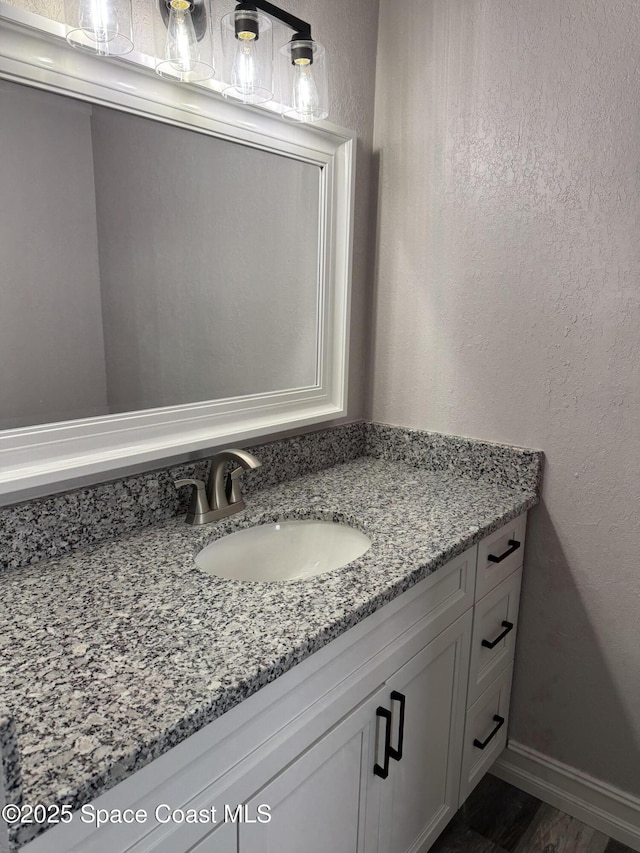 bathroom featuring a textured wall, vanity, and baseboards