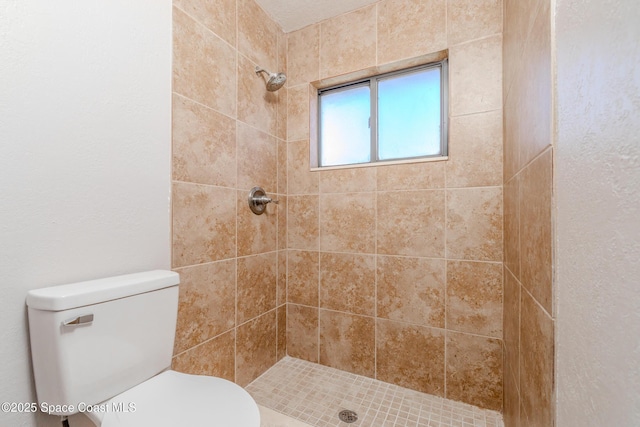 full bathroom featuring toilet and tiled shower