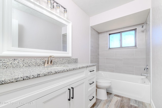 bathroom featuring toilet,  shower combination, wood finished floors, and vanity