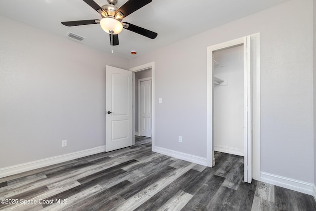 unfurnished bedroom with dark wood-style flooring, a ceiling fan, visible vents, baseboards, and a closet