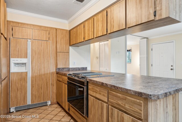 kitchen with visible vents, stainless steel range with gas stovetop, ornamental molding, a peninsula, and paneled fridge