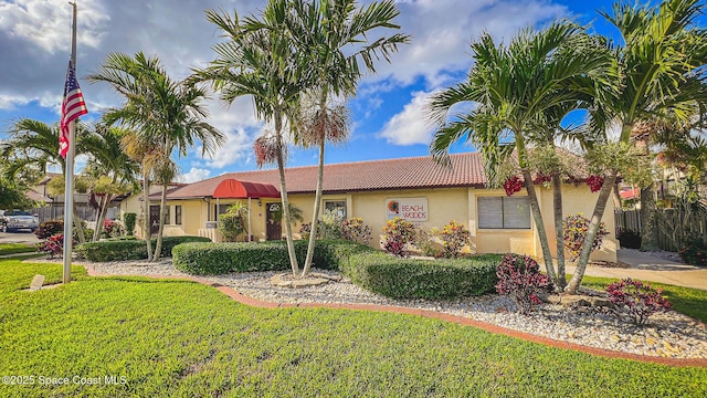 ranch-style home featuring stucco siding, fence, a front lawn, and a tile roof