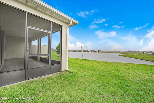 view of yard with a sunroom and a water view