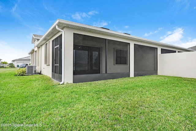 rear view of house featuring a sunroom, central AC unit, and a yard